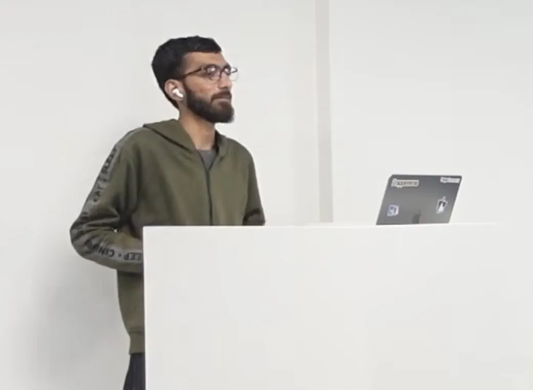 Hussain at a lectern with a laptop, teaching a session